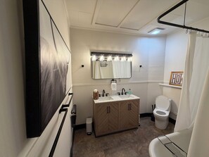 A modern bathroom with a large mirror, a vanity with a sink, and a toilet.