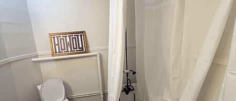 A bathroom with a toilet, shower, and a towel rack.