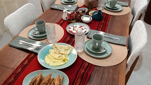 A dining table set with plates, cutlery, and glasses, surrounded by chairs.
