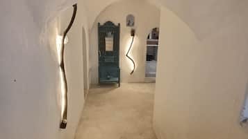 Una stretta scala ad arco conduce a una stanza con una porta verde, un tavolino e una sedia.
