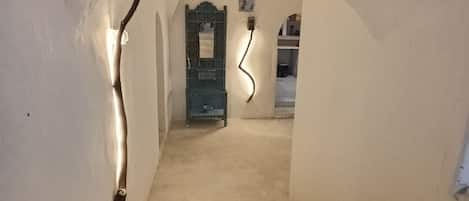 A narrow, arched stairway leading to a room with a green door, a small table, and a chair.