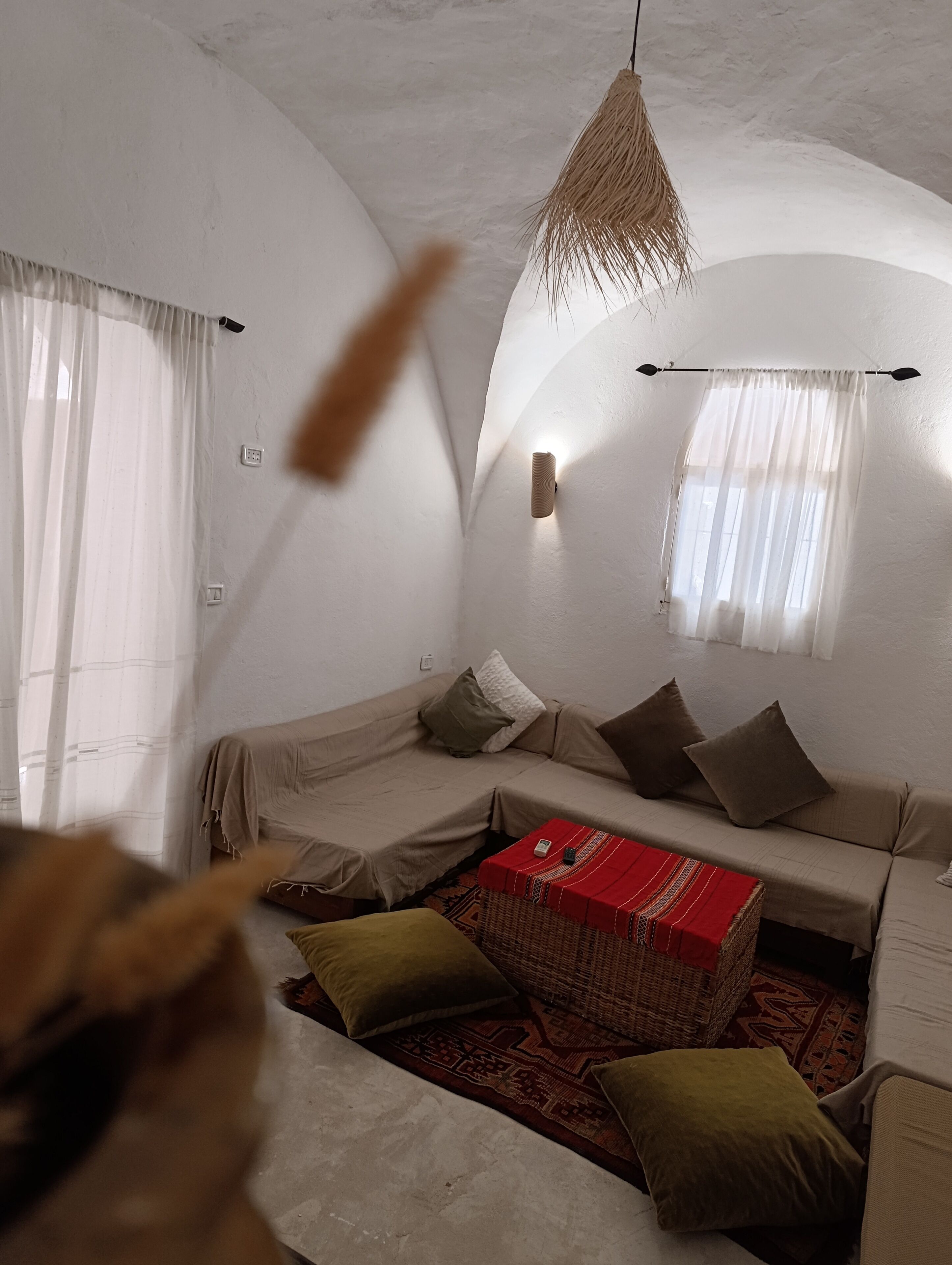 Ein gemütliches Wohnzimmer mit einer Couch, Kissen, einer roten Kiste und einer Pendelleuchte.