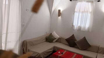 Ein gemütliches Wohnzimmer mit einer Couch, Kissen, einer roten Kiste und einer Pendelleuchte.