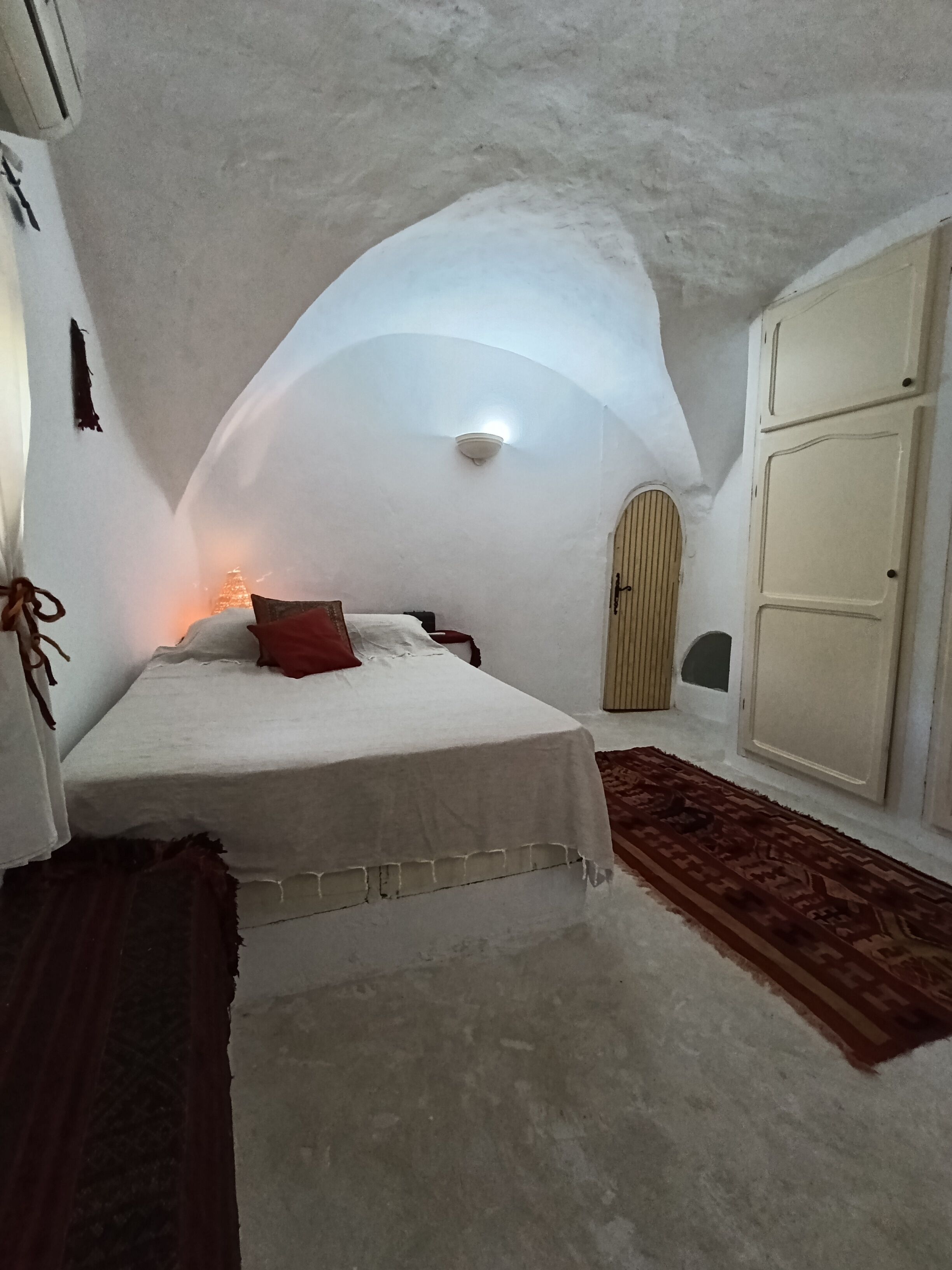 A bedroom with a bed, a wardrobe, and a ceiling light.