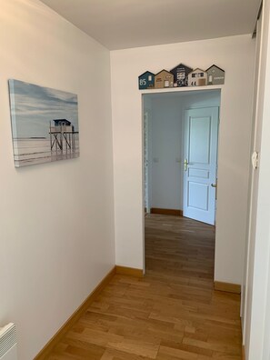 Ein Flur mit Holzboden, einer Tür mit Messinggriff und einem an der Wand befestigten Schild mit Hausnummern.