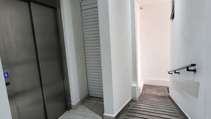 A hallway with a tiled floor, a closed elevator, and a staircase leading to another level. - Huge Private Terrace - Panoramic Bay Views - Walk to the Malecón (Puerto Vallarta)