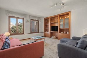 Ett vardagsrum med en soffa, ett soffbord, en tv och en bokhylla.
