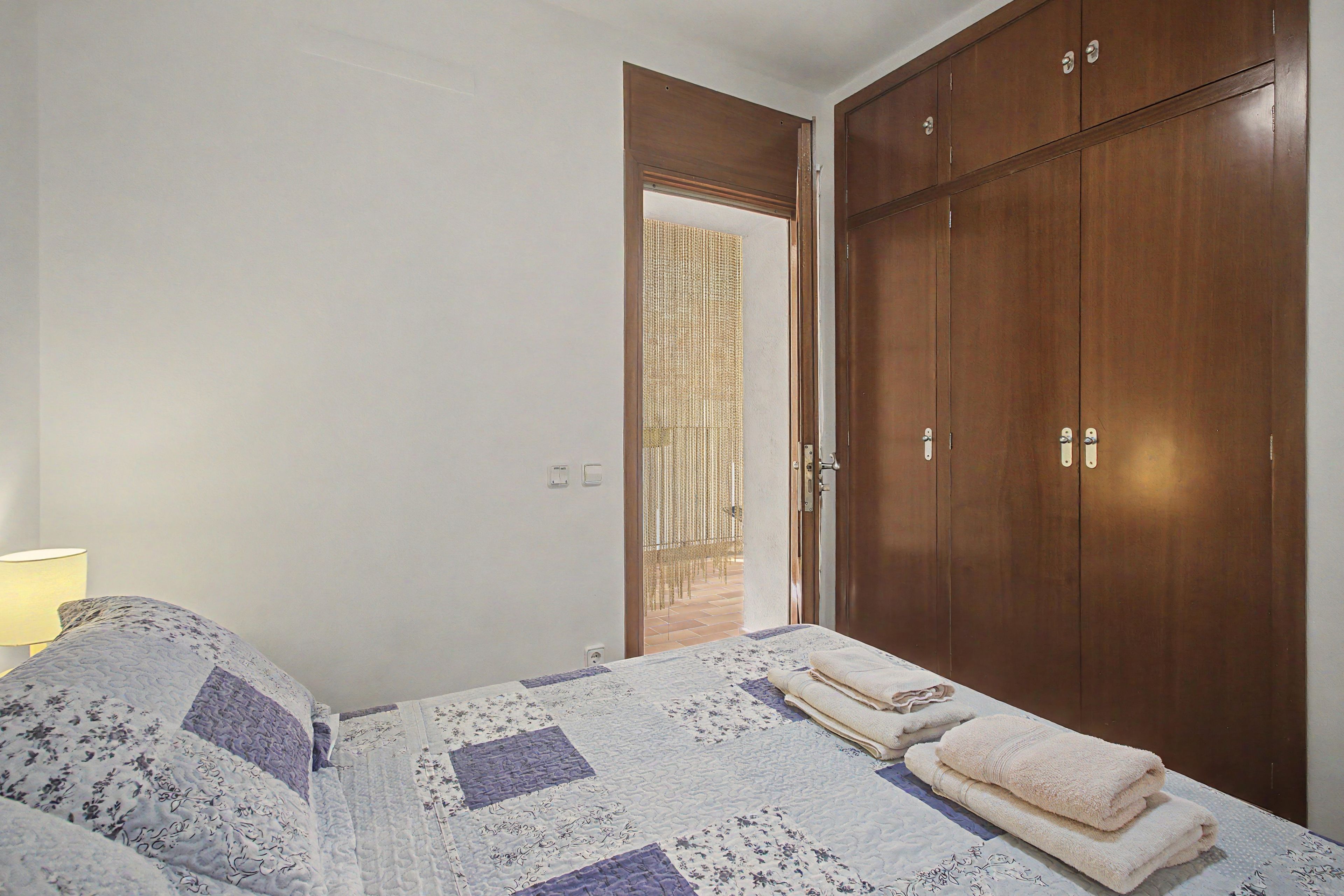 Un dormitorio con una cama, un armario y una puerta que da a un espacio exterior.