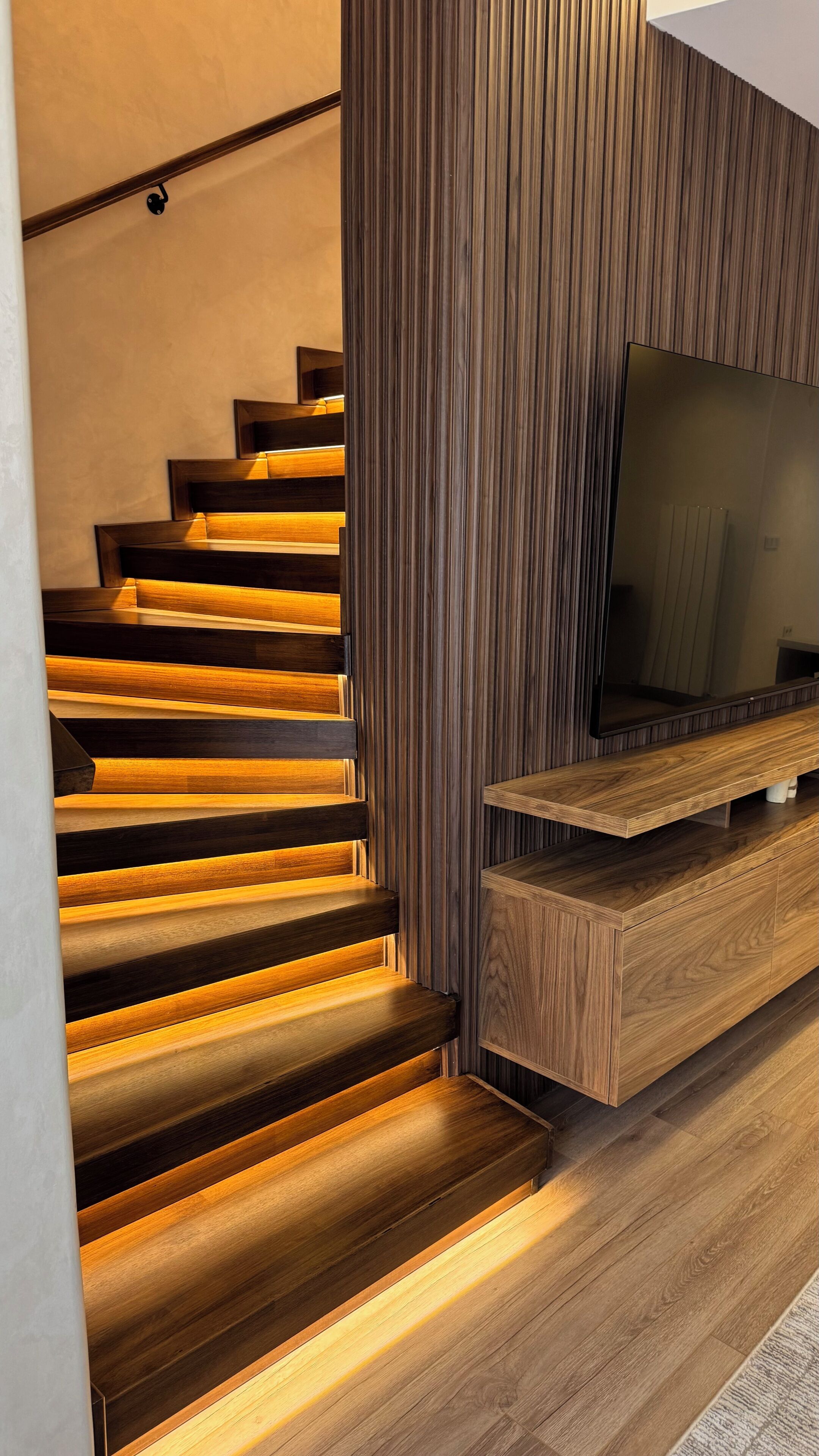 Een trap met houten treden en een ingebouwde tv-plank.