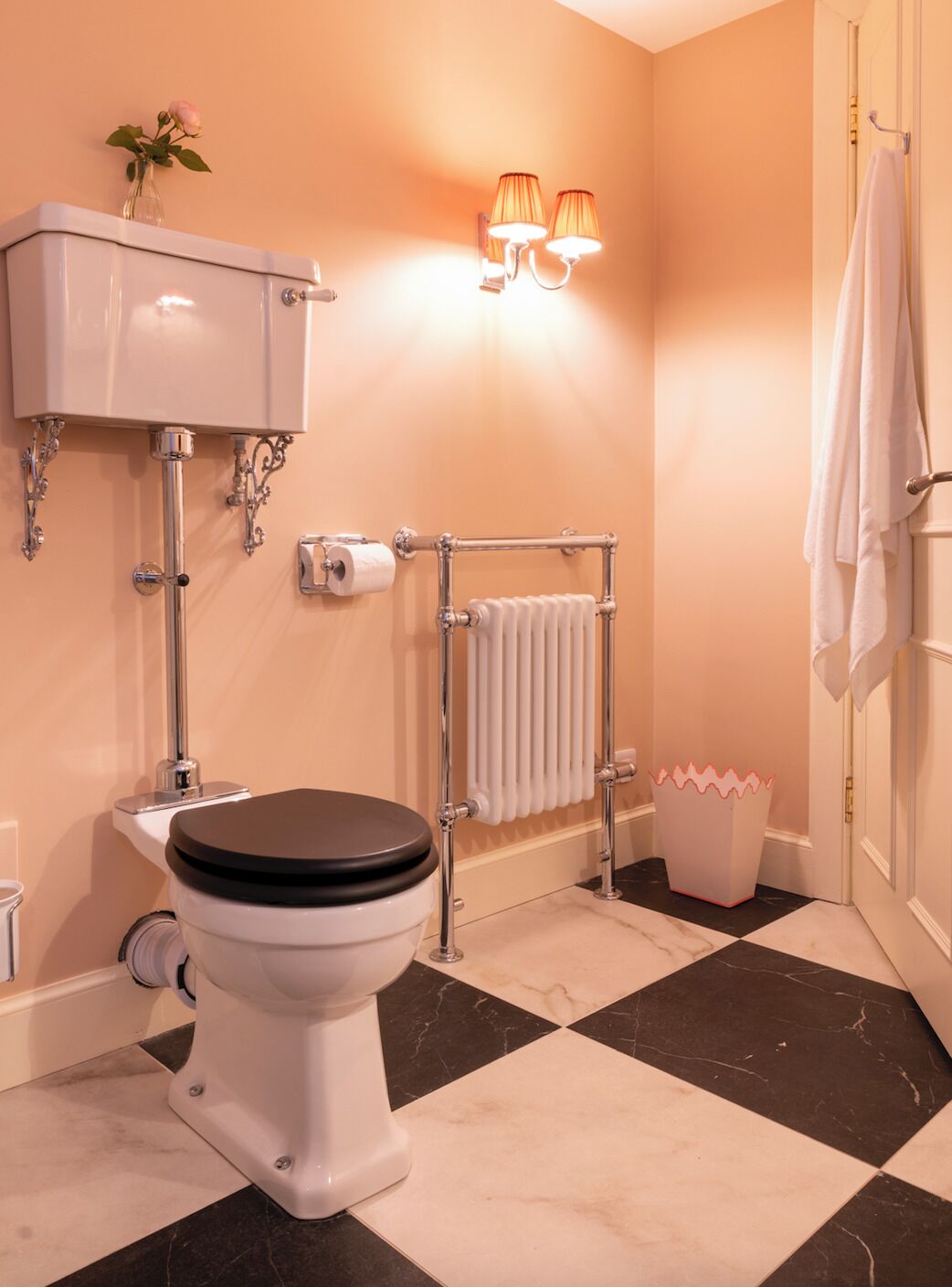A bathroom with a toilet, a towel rack, a radiator, and a trash bin.
