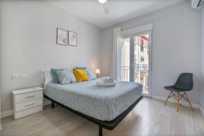A bedroom with a bed, bedside table, chair, and a view of the outside balcony. - Triviño Granada Centro Apartment with Wi-Fi, Air Conditioning and Optional Parking (Granada)