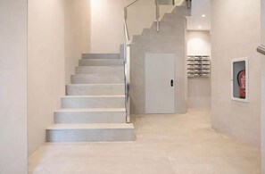 A staircase leading to a door with a fire extinguisher mounted on the wall. - Triviño Granada Centro Apartment with Wi-Fi, Air Conditioning and Optional Parking (Granada)