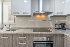 A modern kitchen with a stainless steel range hood, a built-in oven, a coffee maker, and a sink. - Triviño Granada Centro Apartment with Wi-Fi, Air Conditioning and Optional Parking (Granada)
