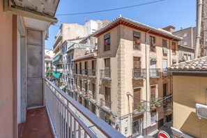A multi-story building with balconies, a visible storefront, and a clear sky. - Triviño Granada Centro Apartment with Wi-Fi, Air Conditioning and Optional Parking (Granada)