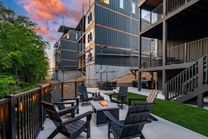 Une terrasse extérieure moderne, aménagée avec du mobilier d’extérieur et un foyer.
