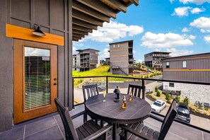 A balcony with a table and chairs, overlooking a residential area with modern buildings. - Next Play Clubhouse | Waterpark Resort & Game Room (Sevierville)