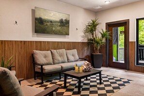 Ein stilvoller Lounge-Bereich mit einer Couch, einem Couchtisch und einem karierten Teppich.