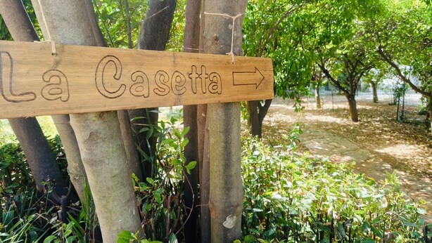 Et træskilt med teksten 'La Casetta' og en pil, der peger mod højre, som viser vej.