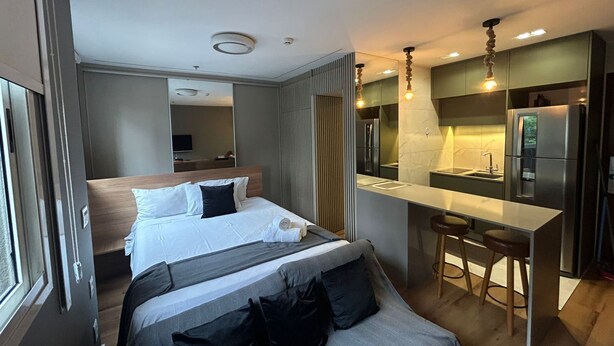 Een moderne hotelkamer met een bed, een kitchenette en een badkamer.