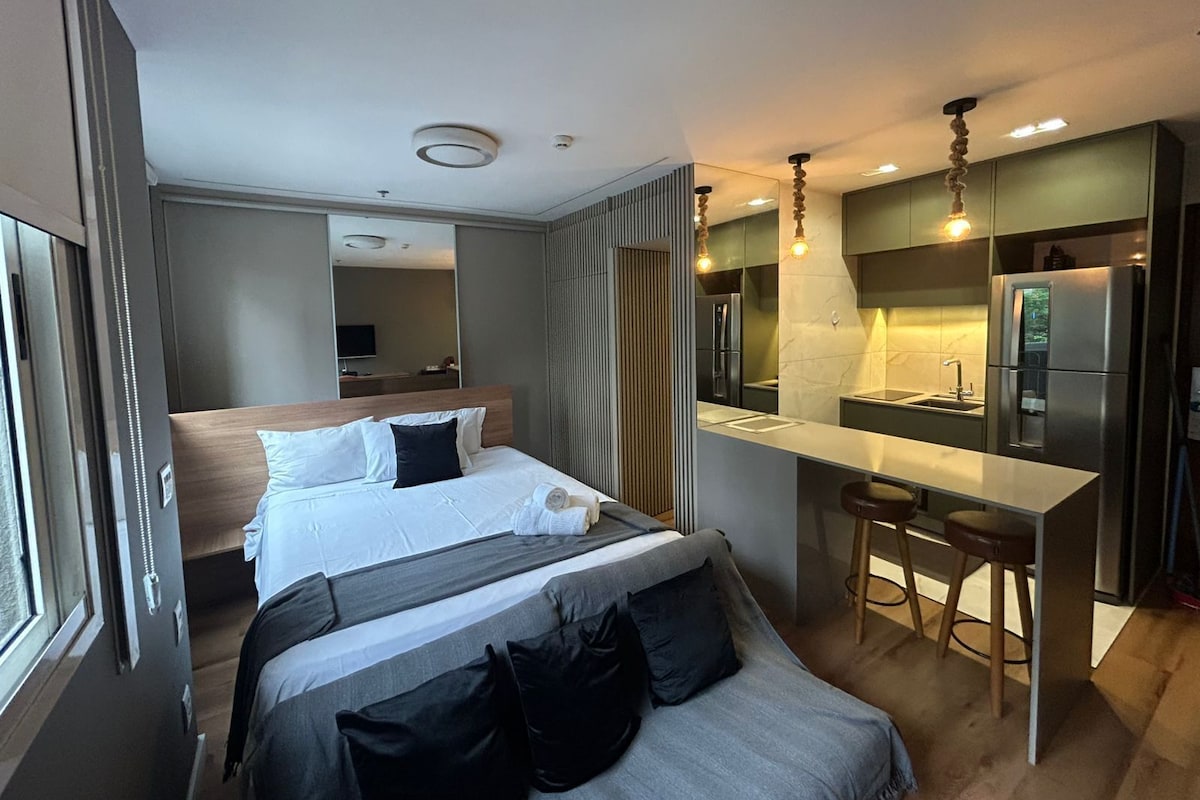 Ein modernes Hotelzimmer mit Bett, einer kleinen Küchenzeile und einem Badezimmer.