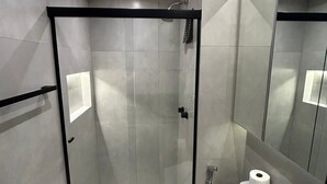Een moderne badkamer met een douchecabine van glas, een toilet en een grote spiegel.