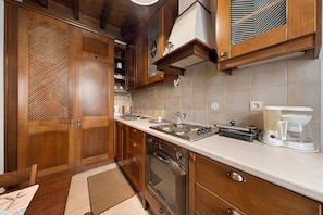 A kitchen with wooden cabinets, a stove, an oven, and a coffee maker. - Casabella Apartment in Corfu Town with Air Conditioning (Corfu)