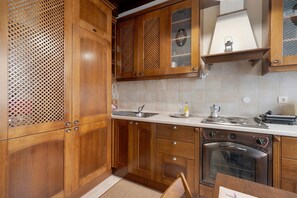 A kitchen with wooden cabinets, a sink, a stove, and a countertop. - Casabella Apartment in Corfu Town with Air Conditioning (Corfu)