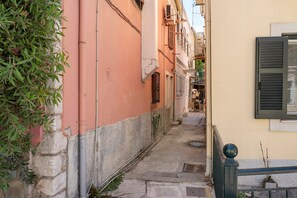A narrow alleyway with buildings on either side, a metal railing, and a small step leading down to a street. - Casabella Apartment in Corfu Town with Air Conditioning (Corfu)