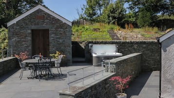 Un edificio de piedra con una puerta, un jacuzzi y un patio con sillas y una mesa.