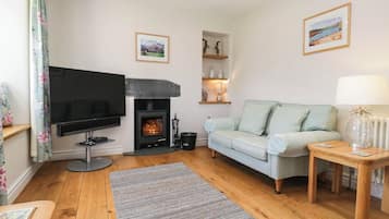 A living room with a fireplace, a sofa, a television, and a small table with a lamp.