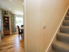 A staircase leading to a landing with a dining area in the background.