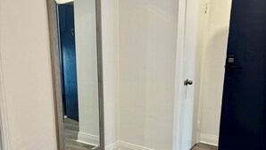 En hall med en stor spegel, en dörr med ett kodlås och en svart matta på golvet.