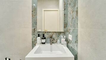 Un bagno con un lavabo bianco, una schiena di marmo e uno specchio sopra.