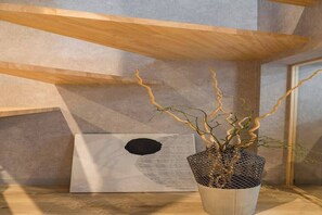 A modern interior with a wooden ceiling, a concrete wall, and a potted plant with twisted branches. - Designer-designed, accommodate 6 people / 8 minutes from Shinjuku and Shibuya. (Setagaya City)