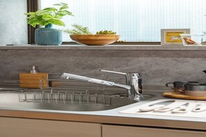 A modern kitchen with a stainless steel sink, a dish rack, a wooden bowl with plants, and a coffee drip bag on the counter. - Designer-designed, accommodate 6 people / 8 minutes from Shinjuku and Shibuya. (Setagaya City)