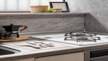 A modern kitchen with a gas stove, a coffee maker, and a cutting board.