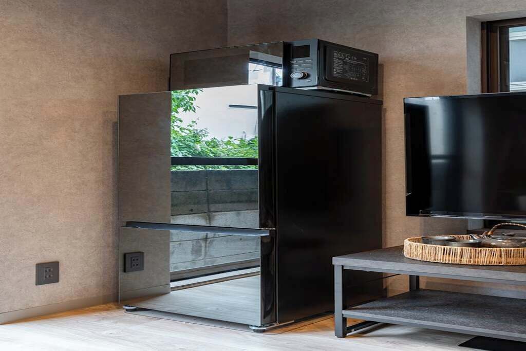 A modern kitchen with a built-in refrigerator and a flat-screen TV on a stand.