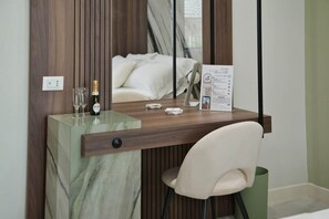 Een hotelkamer met een houten bureau, een stoel, een fles wijn, glazen en een menukaart op de tafel.