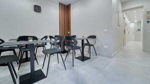 A modern conference room with a long table, multiple chairs, a clock on the wall, and a wooden accent wall.