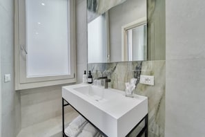 A modern bathroom with a large mirror, white sink, and marble backsplash. - Deluxe Double Room (Rome)