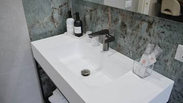 Un bagno moderno con un lavandino bianco, un rubinetto nero e uno schienale in marmo.