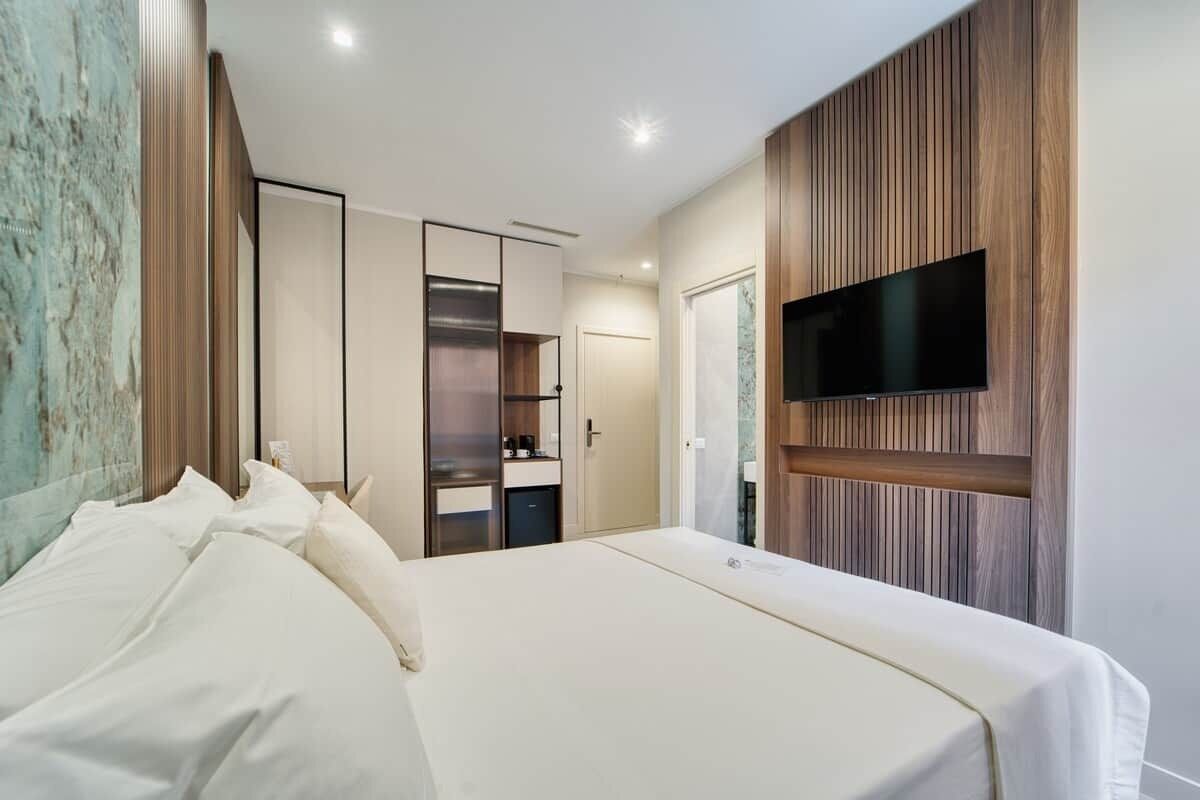 Una camera d'albergo con un letto, una televisione a parete e un armadio.