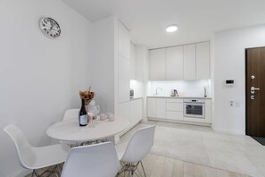 Eine moderne Küche mit weißen Schränken, einem eingebauten Ofen und einem Essbereich mit einem runden Tisch und Stühlen.