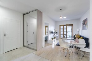 Un salon moderne comprenant un coin repas, une porte-fenêtre coulissante donnant sur un balcon et un canapé blanc.