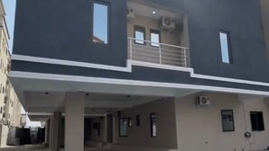 Un edificio moderno de dos pisos con techo plano, ventanas amplias y zona de estacionamiento techada.