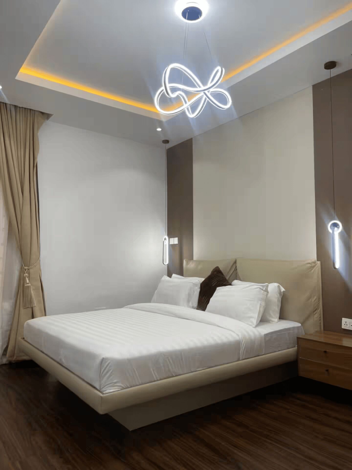Un dormitorio moderno con cama, mesitas de noche y una lámpara en el techo.