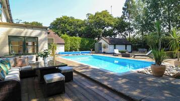 A swimming pool with a deck, lounge chairs, and a small building in the background.