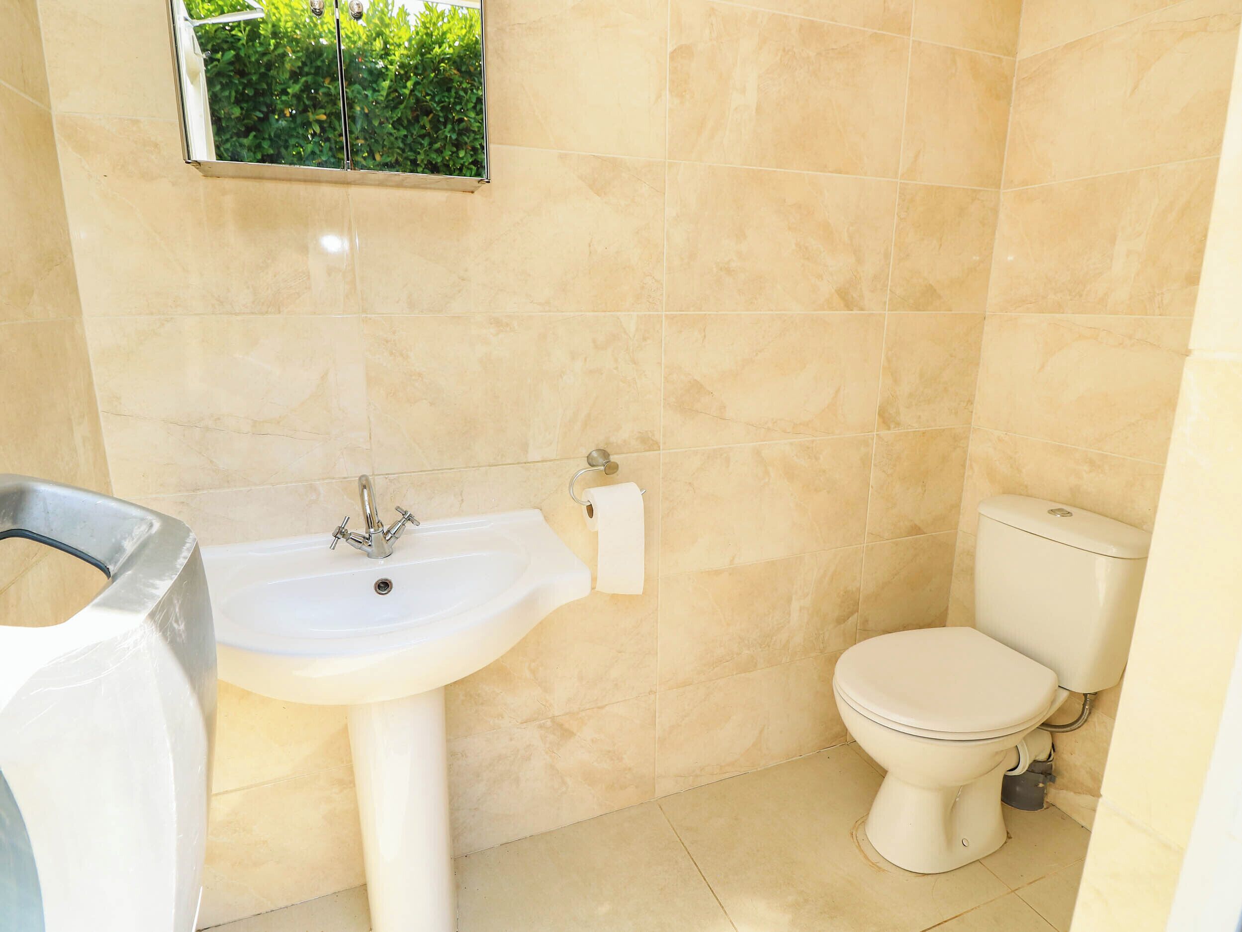 Une salle de bain équipée d’un lavabo, de toilettes et d’une fenêtre donnant sur un espace verdoyant.