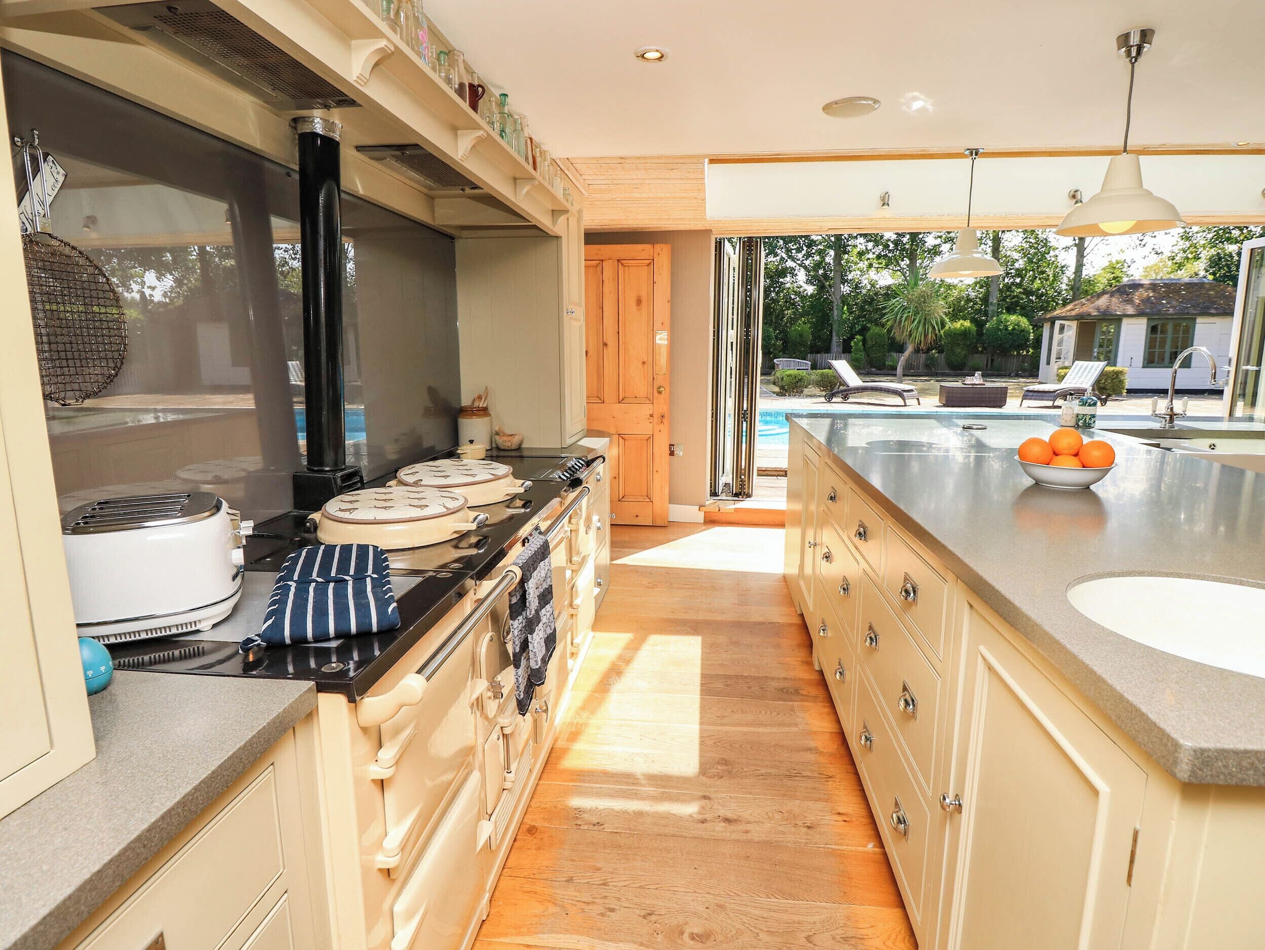 A kitchen with a stove, oven, and a large island with a bowl of fruit.