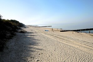 A sandy beach with a clear sky, a pier extending into the water, and a few people in the distance. - Studio for 2 people, Dziwnówek (Dziwnówek)
